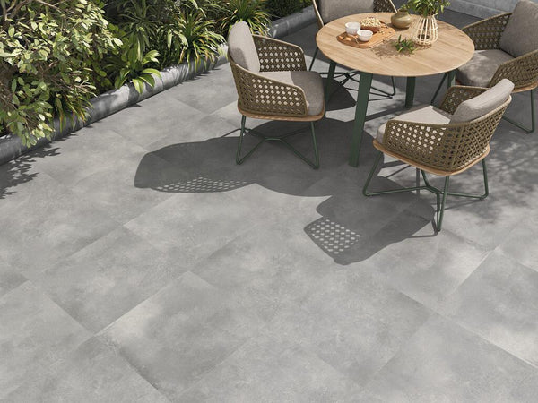 Grijze keramische tegels op groot formaat op een modern terras met tafel en stoelen